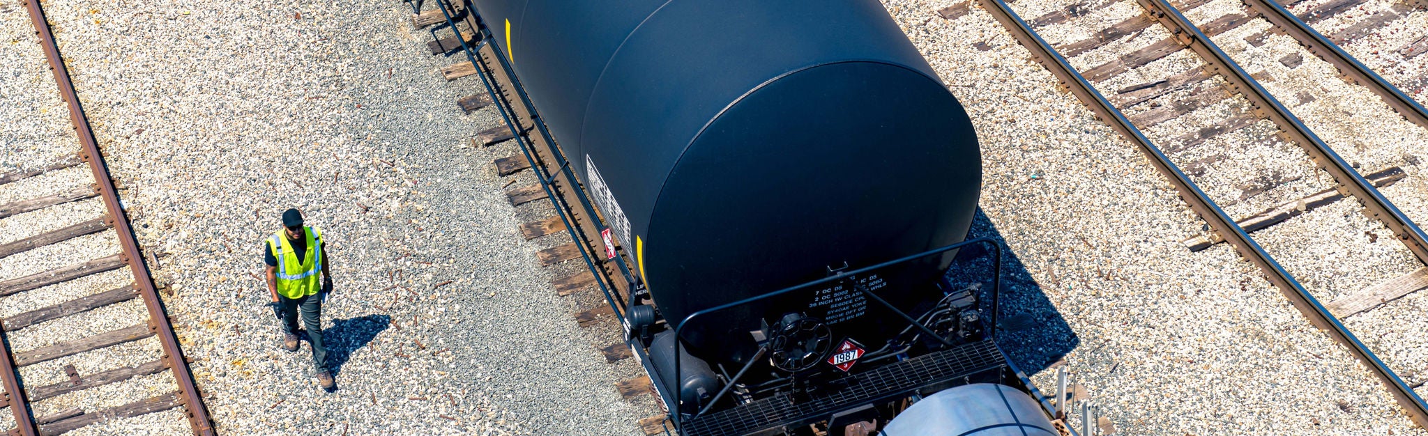 Aerial image of Norfolk Southern train car on tracks transporting low carbon fuels next to an employee