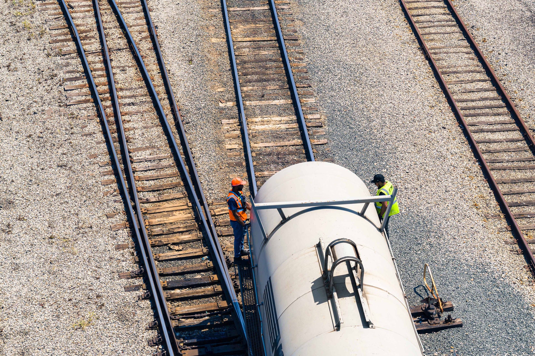 Norfolk Southern white chemical railcar at railyard facility on tracks with employees standing next to is