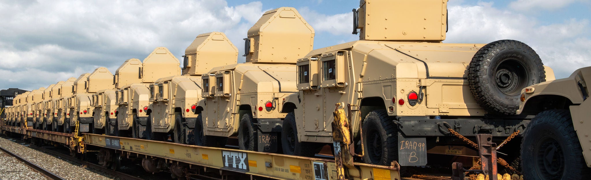 Armored vehicles shipping military equipment Multiple armored vehicles on an open train car showing ways to ship military equipmen