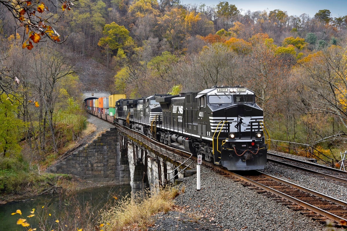 Photography and railroading go well together. One seems to complement the other — and for Locomotive Engineer Lance Myers, he’s often on both sides of the coin.,“I’ve been with NS for 15 years,” Myers says. “I started as a conductor trainee and made my way to conductor and then locomotive engineer. I’m proud of the work that I do, and enjoy catching our trains in action through photography when I’m not on the job.”,In one of those moments, Myers caught an NS double-stack intermodal train exiting the Spruce Creek Tunnel along the Juniata River in Pennsylvania. Led by one of our DC-to-AC converted locomotives, this train is moving international containers bound for New Jersey on our Premier Corridor.,Myers’ railroading career has been spent based in Altoona, Pennsylvania, where he operates road trains to and from Harrisburg and Pittsburgh, Pennsylvania. He frequently serves on a crew known as the Altoona Helpers, assisting NS trains over steep grades of the Allegheny Mountains.