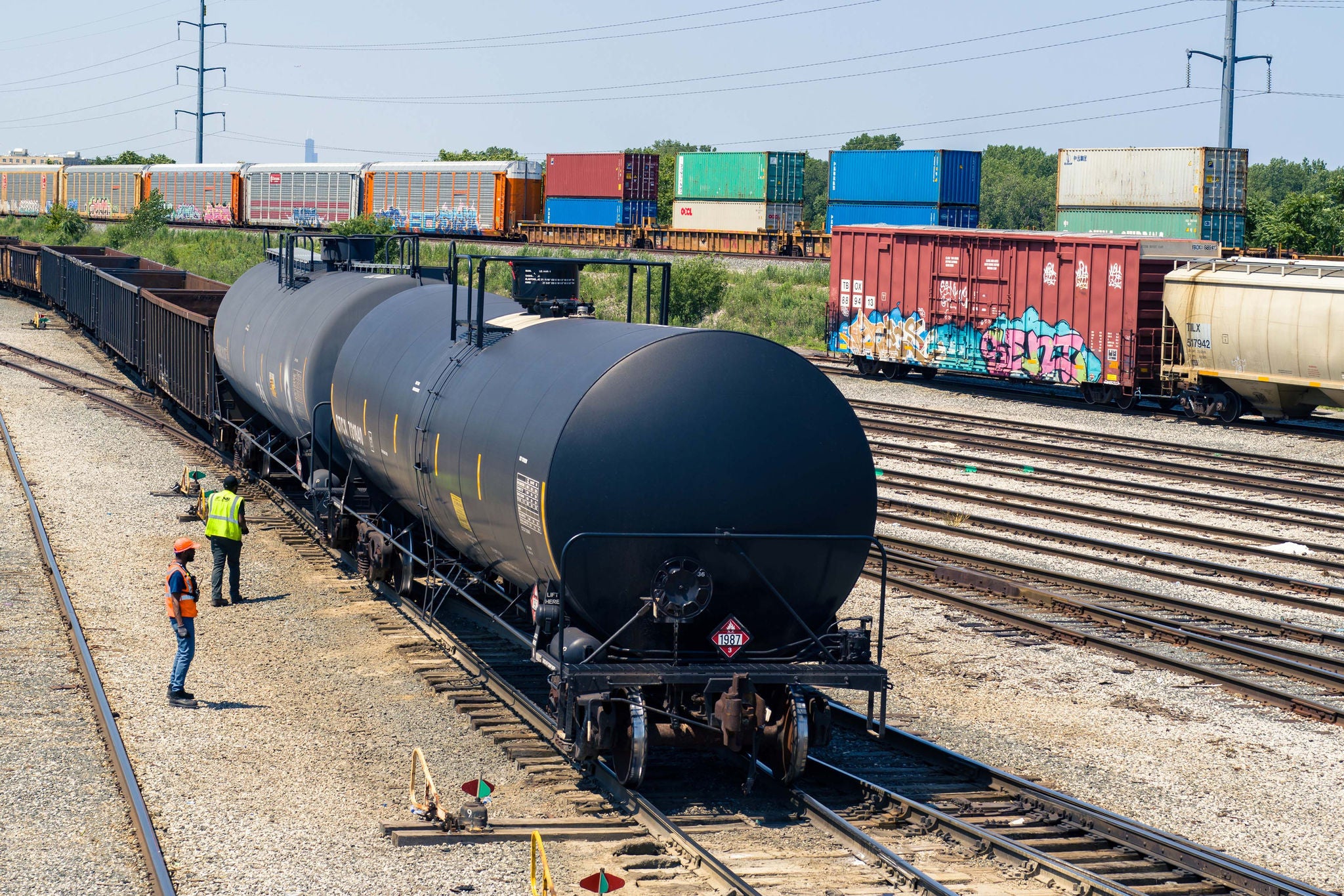 Two Norfolk Southern employees in security vests looking at a container on a train transporting low carbon fuels