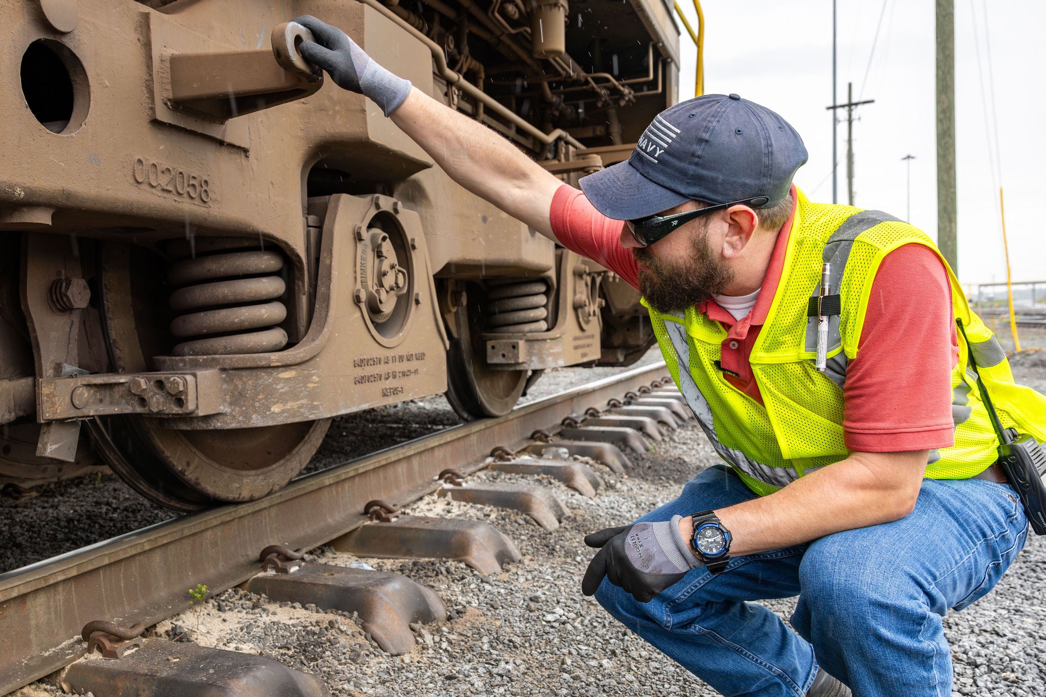 Man in safety vest squatting down looking at the base of a train helping their customer centric strategy