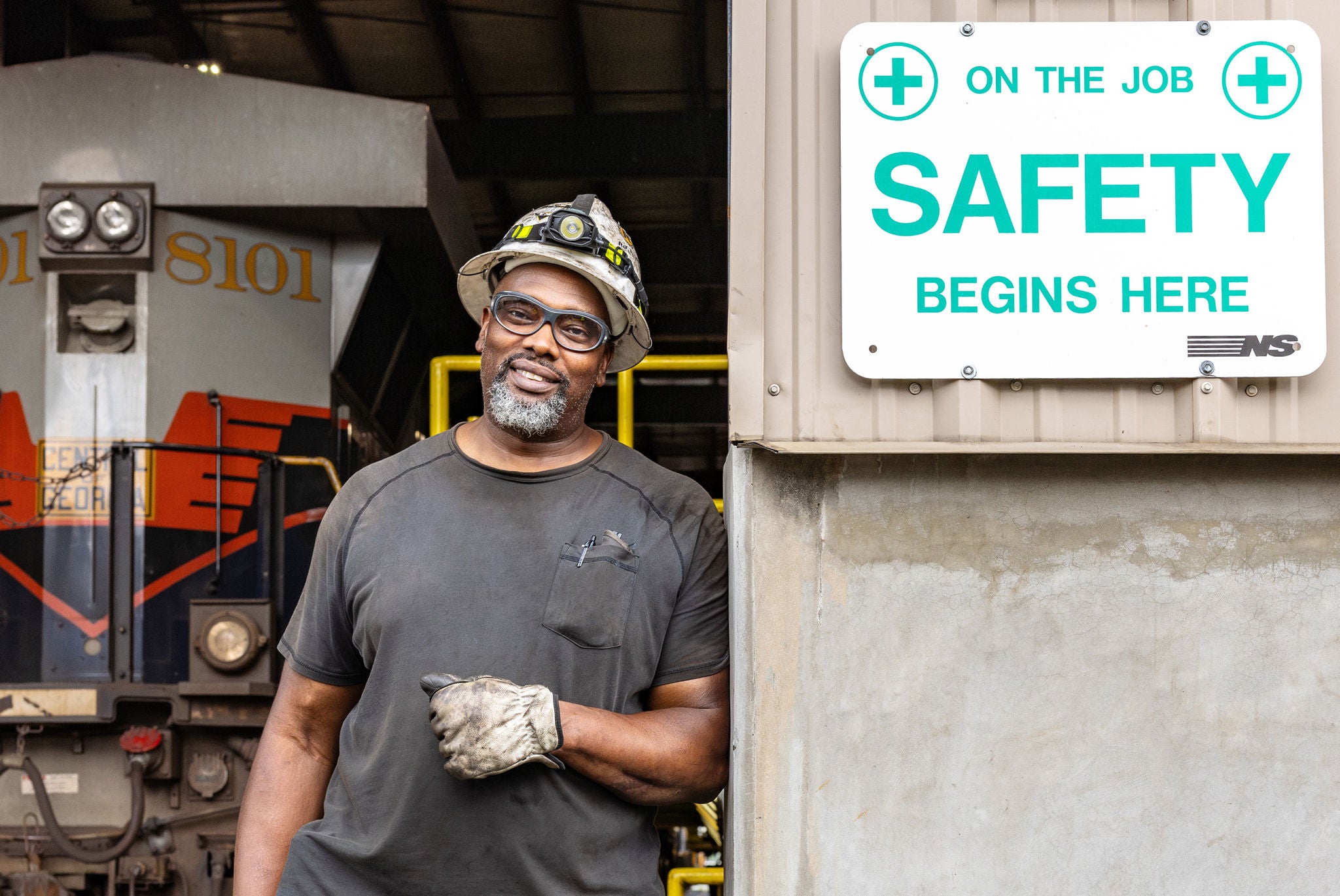 norfolk southern craft employee in railway job in maintenance shop with safety sign begins here sign