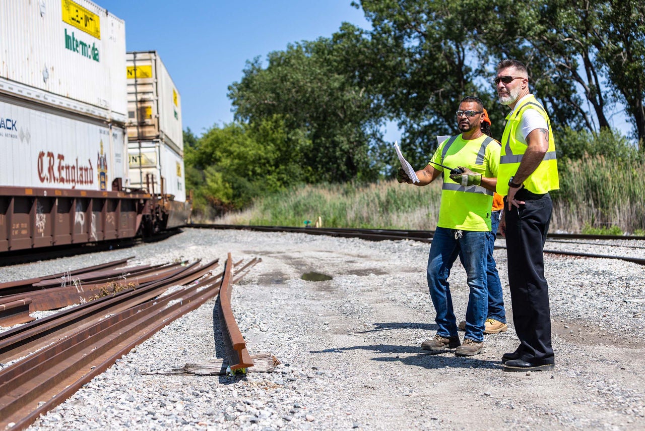 Norfolk Southern crew discuss railcar logistics outside next to train track