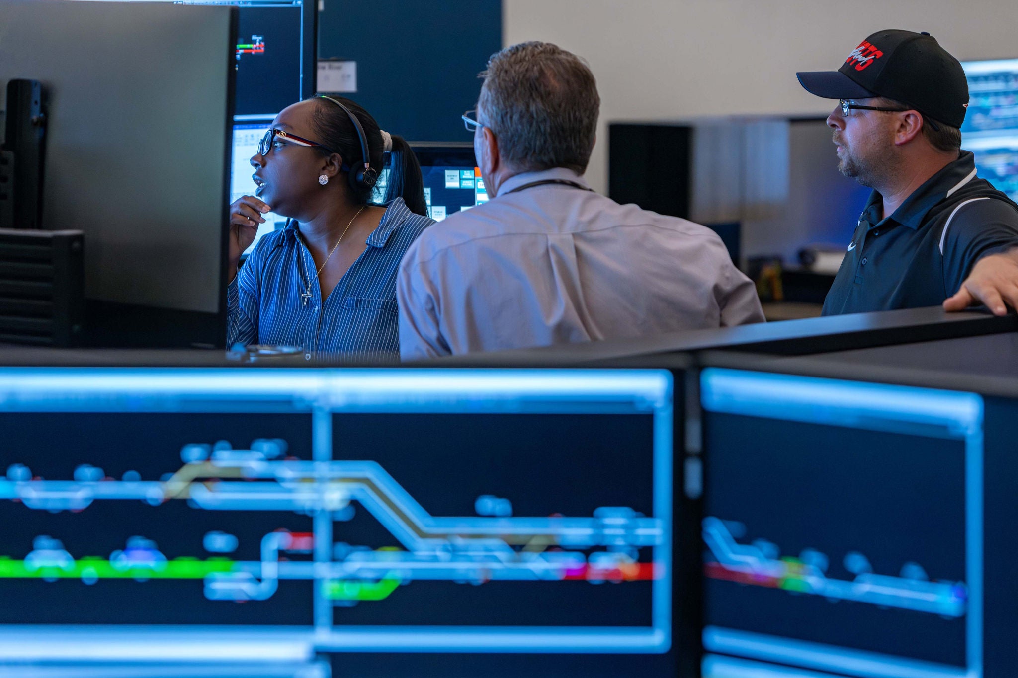 Three Norfolk Southern employees working at the company technology office gather around computers and discuss infrastructure technology plans.