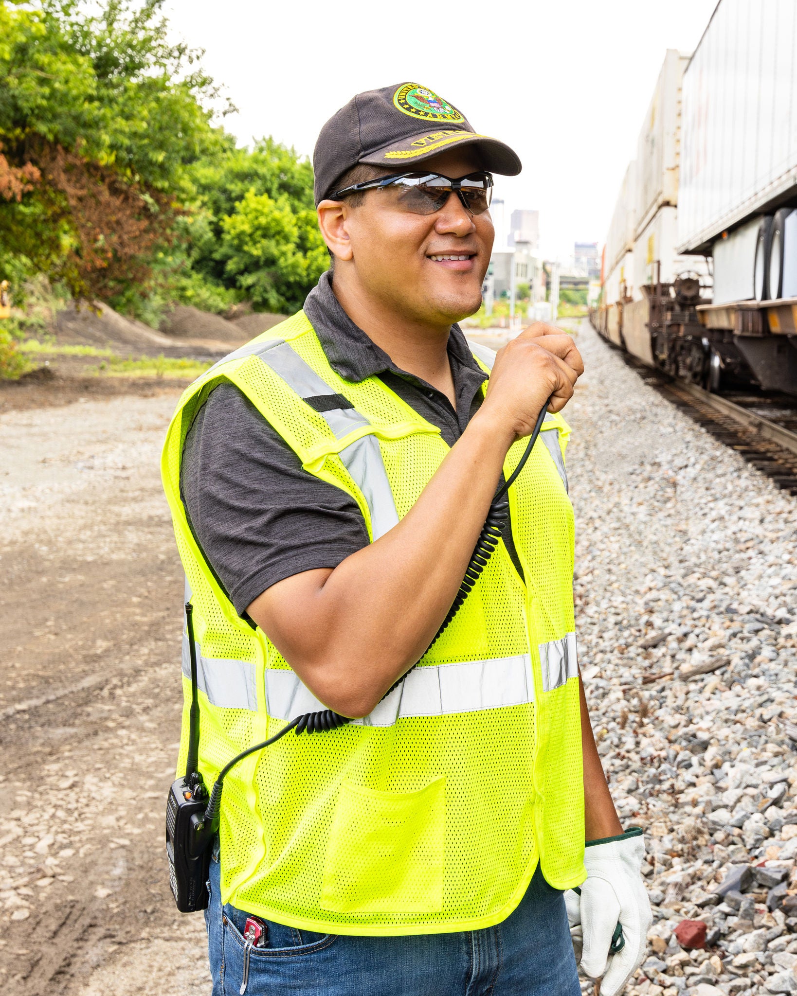 norfolk southern craft employee in railway job and dispatcher job wearing yellow vest and sunglasses using handheld transceiver