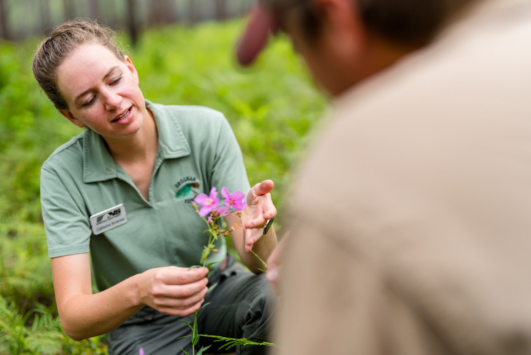 Norfolk Southern employee using sustainability practices in rail shipping in a field holding a flower