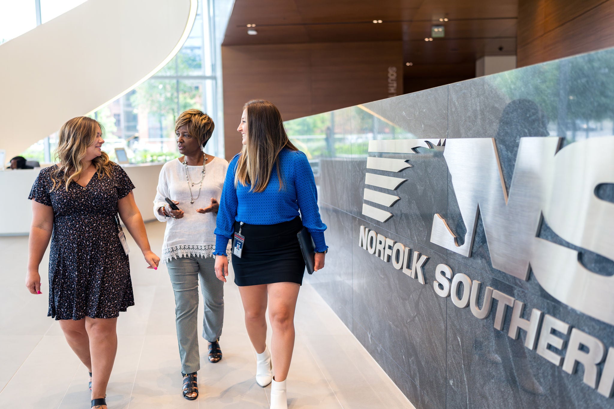 Three Norfolk Southern employees converse in the headquarters lobby showcasing the railway company’s inclusive workplace culture. 