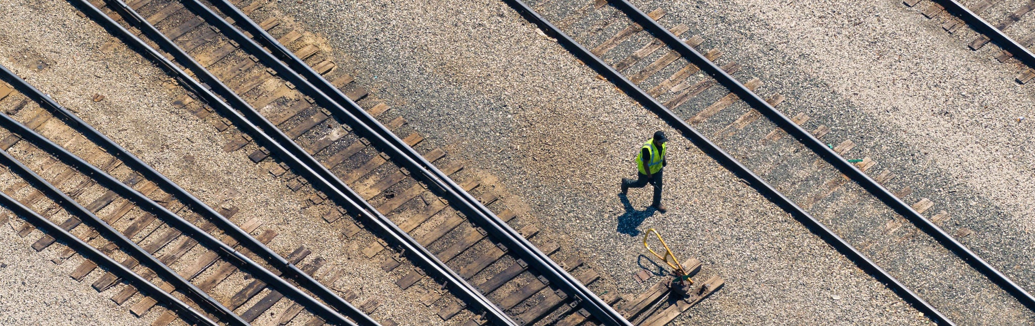 Image alt text: Empty tracks with a person walking by waiting for a train with chemicals transported by rail 