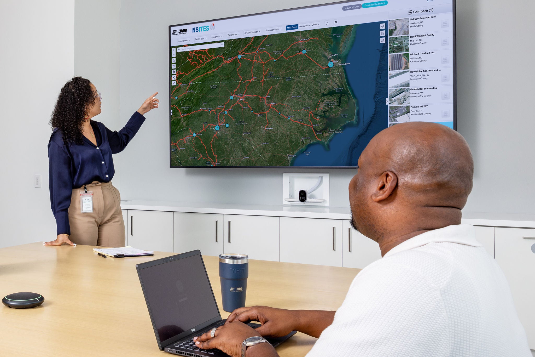Two Norfolk Southern employees discussing the intermodal transportation company’s railroad network map. 