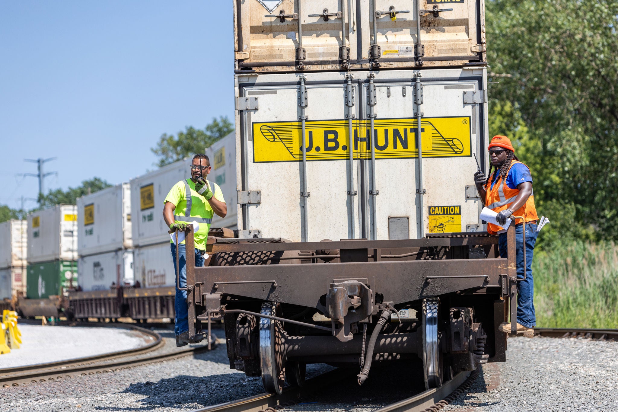Norfolk Southern craft employees riding train with handheld transceivers in railway jobs
