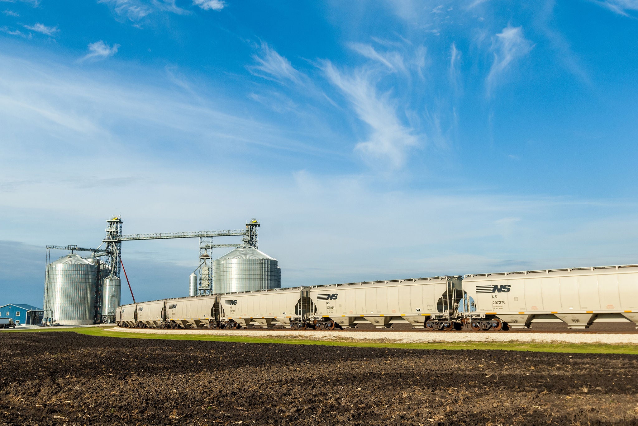 Train on track near silo in an agricultural setting by a field, showing ways to find your shipping industry