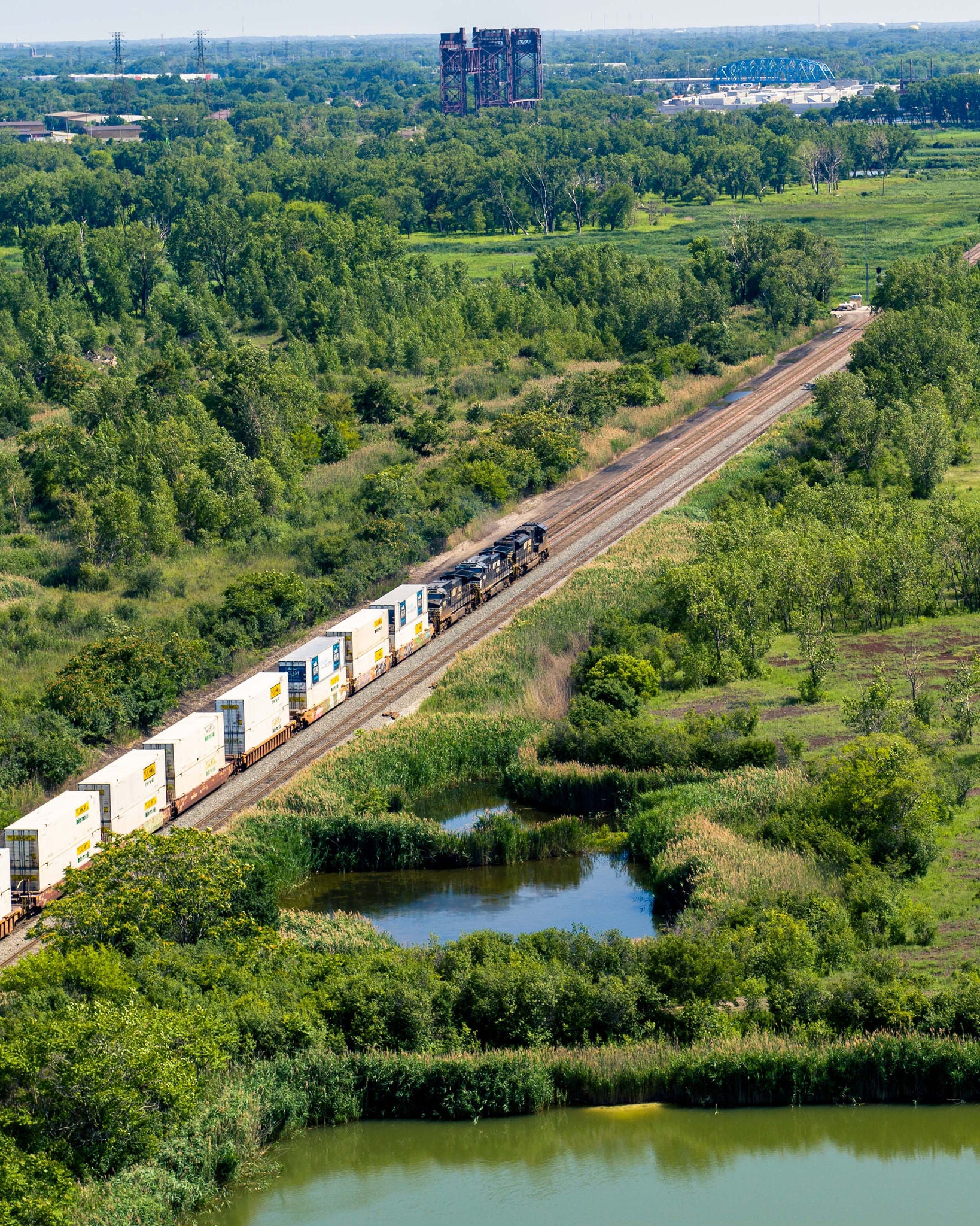 Aerial view of train passing through an industrial development wooded site