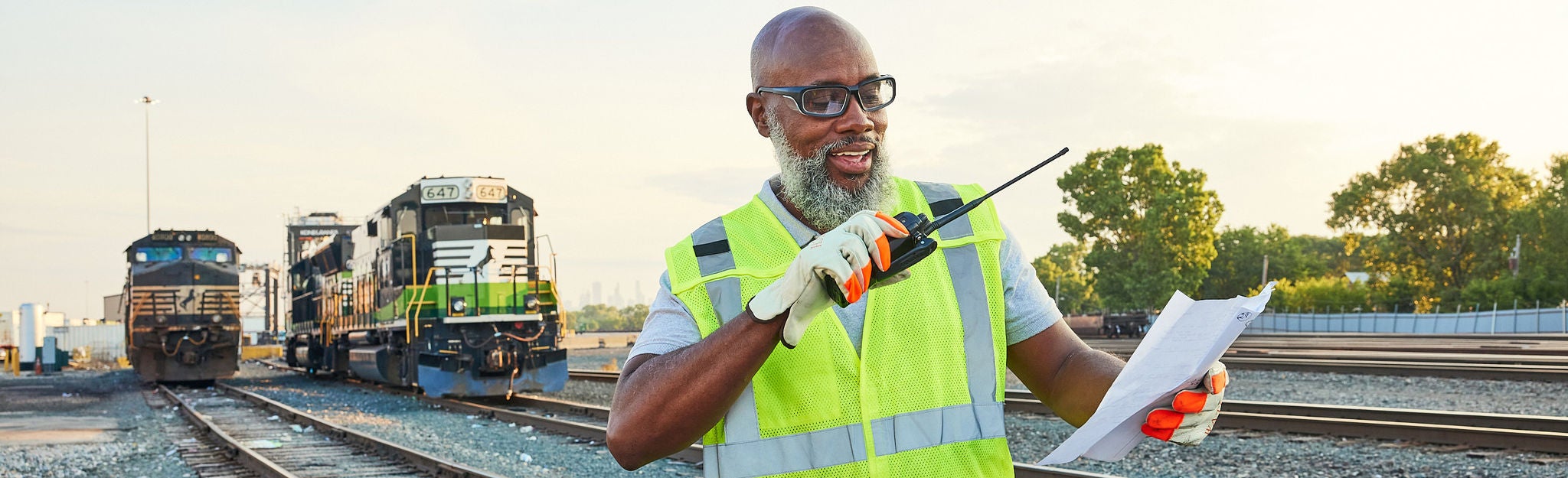 Norfolk Southern Strategy Better Way Forward. Close up of Norfolk Southern employee in safety vest standing on the front of an eco train thinking about customer centric strategy