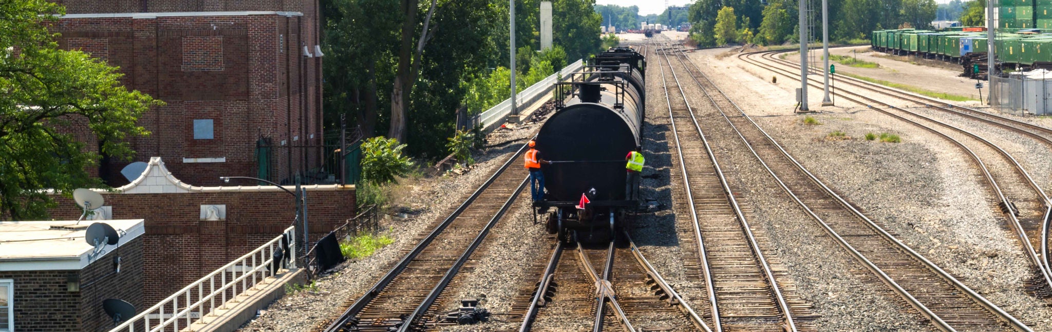 Rear aerial view of a train transporting low carbon fuels driving down a track with Norfolk Southern employees on the back