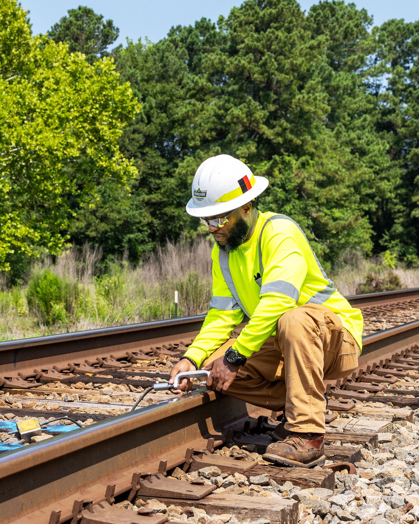 Man in safety vest bent down inspecting train tracks showing Norfolk Southern’s customer centric strategy in acti