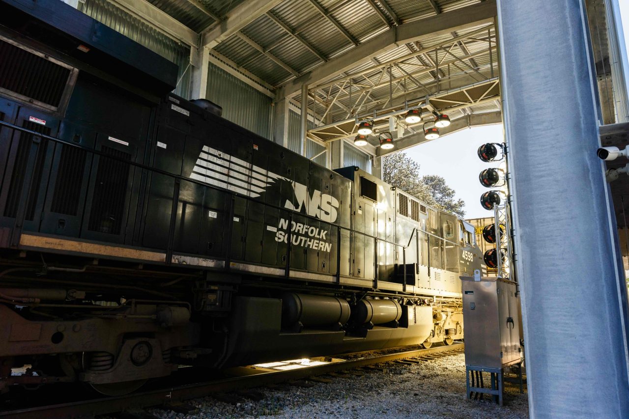 Rail road crew members safely standing on front of Norfolk Southern train.