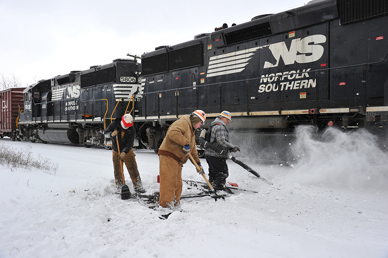 A Norfolk Southern maintenance-of-way crew clears snow from track,switches as a local NS train out of Altoona, Pa., arrives at an interchange yard,in Hollidaysburg, Pa. Chris Boast, electric welder, handles a snow,blower, Nick Holsopple, electric welder—helper, uses a shovel, and,Joe Barr, section foreman, follows up with a heavy-duty broom.MOW-snow-3