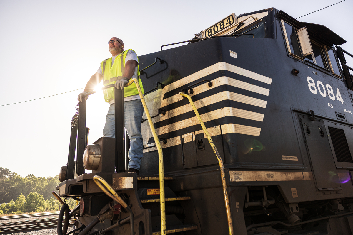 2025 Brand Photography - employees - craft conductor standing on the front of a locomotive in yard